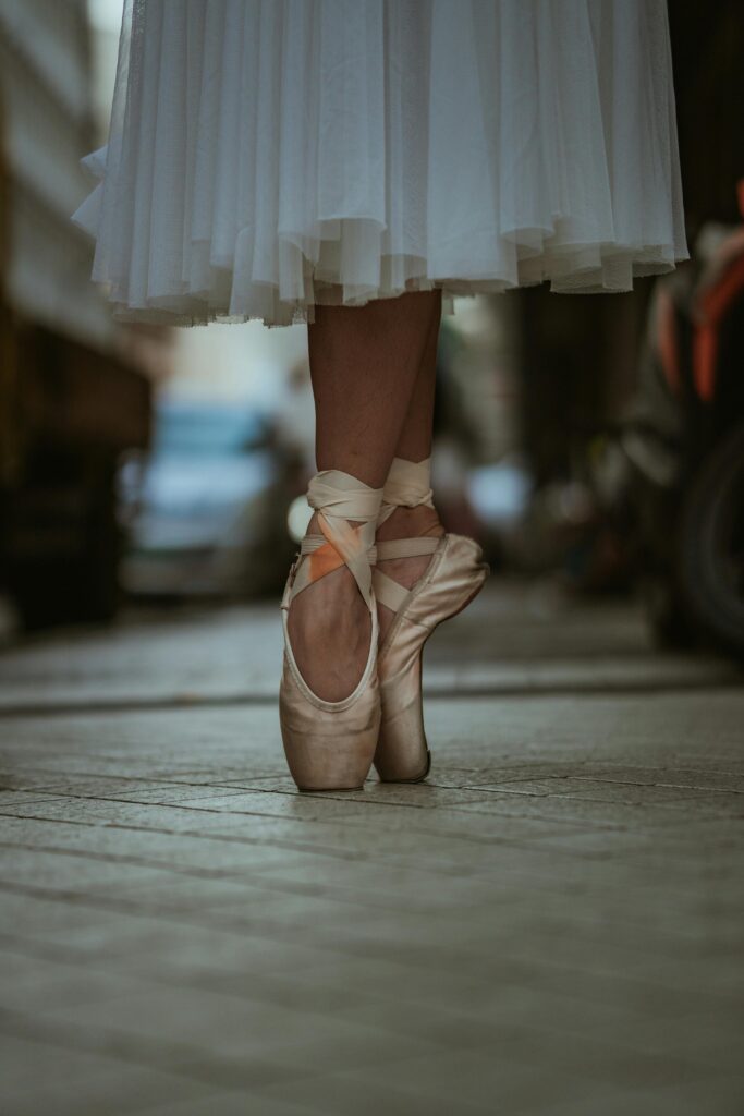 Danseuse de ballet en pointes dans une rue urbaine, mettant en valeur l'élégance et l'équilibre.